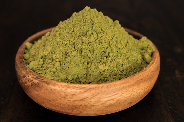 Green Hulu plant powder from indo shown fresh in wooden bowl