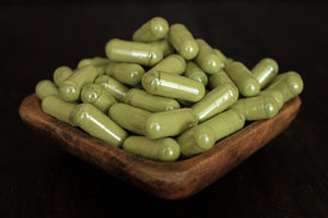 Super white powder in 1000 mg capsules in a wooden bowl close up